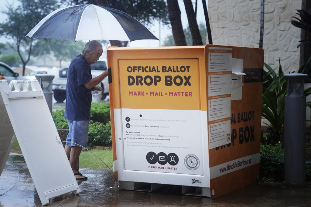A voter avoids the wait to vote in person and drops his ballot in the Official Ballot Drop Box at Kapolei Hale Tuesday, Nov. 5, 2024, in Kapolei. Elections administrator for the City and County of Honolulu Rex Quidilla says it’s been a long time since it rained on Election Day. (Kevin Fujii/Civil Beat/2024)