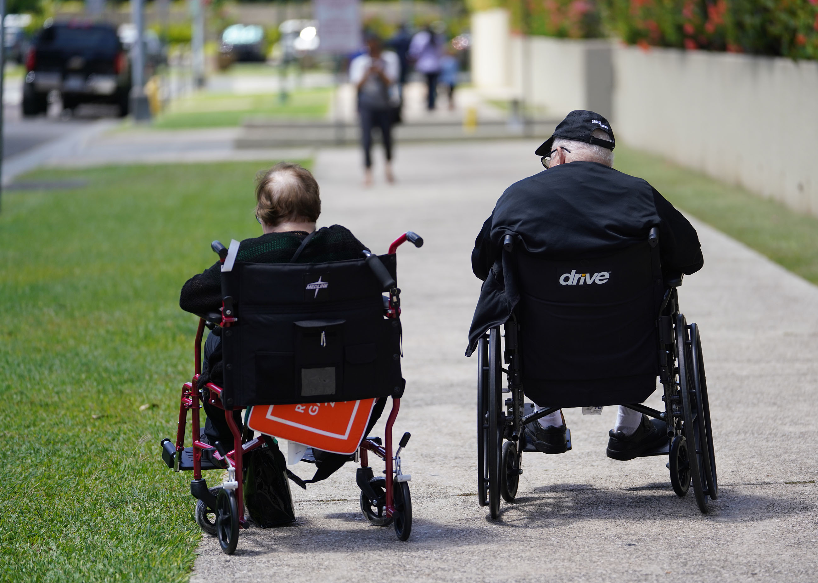 Elderly Couple on wheelchairs wait for the family members to feed the meter near Halekauwila street.