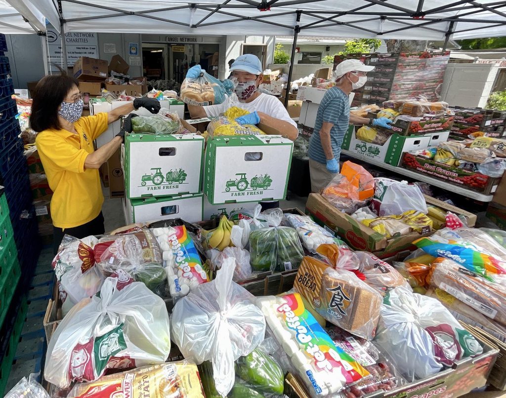 Yolisa Ishibashi (left) and Ellsworth Fujii of the Hawaii Kai Lions International club volunteer, to pack bags of fresh produce, at the Angel Network Charities in Aina Haina Thursday, November 4, 2021. The Angel Network Charities foodbank provides perishable and non-perishable food items for struggling elderly, children, individuals, and families on the 1st and 3rd Thursdays of every month. ( Ronen Zilberman photo Civil Beat)